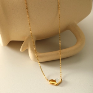 French style heart necklace with gold plating and white shell inlay on a ceramic cup