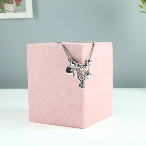 Detail of silver snake chain necklace with key pendant on pink velvet jewelry stand