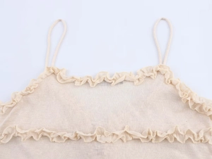 Detail of a beige knit camisole featuring delicate double ruffles and fine ribbed texture
