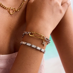 Bracelet chaîne trombone bicolore avec croix et collier cœur portés par un mannequin