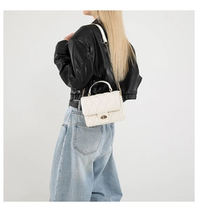 Rear view of model wearing white quilted crossbody bag with gold chain strap detail