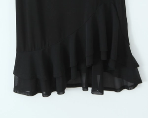 Detailed view of the black chiffon ruffle hem with translucent mesh patchwork layers