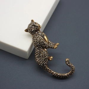 Vintage leopard brooch with black pavé crystals and gold plating on a white stand
