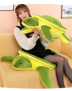 Two realistic green sea turtle plush toys in different sizes shown on a yellow sofa