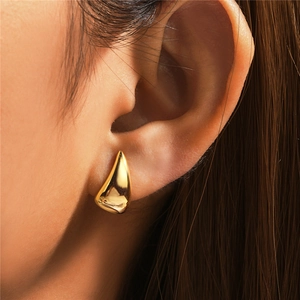 Close-up of a polished gold teardrop earring with smooth metallic mirror finish