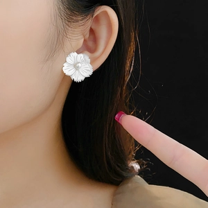 Gros plan d'une boucle d'oreille fleur élégante avec nacre et perle centrale sur l'oreille