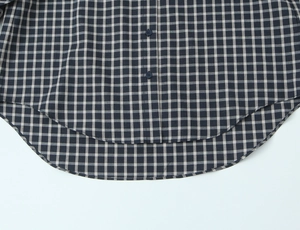 Detailed close-up of curved hem and plaid pattern on a casual cotton linen shirt