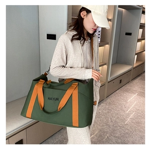 Detail of army green travel bag with orange handles and HAYUN branding for yoga