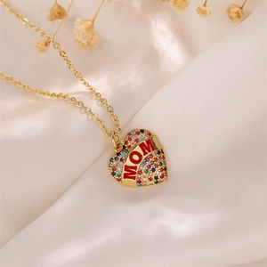 Macro shot of gold heart MOM pendant with colorful zircons on white silk fabric