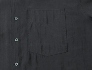 Detail of beaded poplin shirt showing chest pocket, buttons and linen fabric texture