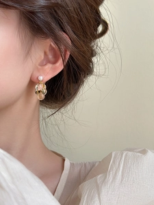 Gros plan de boucles d'oreilles grappes dorées avec perles de résine sur un modèle