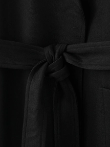 Detailed close-up of the black twill fabric texture and tied waist belt on the coat