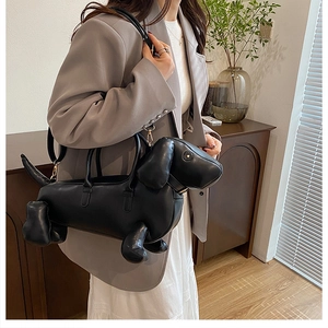 Dachshund-shaped black handbag with gold hardware styled with a grey blazer and dress