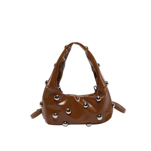 Detail view of brown glossy leather underarm bag with large silver ball rivets