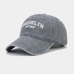 Close-up of white Brooklyn embroidery on washed dark grey cotton baseball cap texture