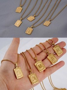 Vista detallada de colgantes de letras hip hop bañados en oro 18K con cadenas de acero