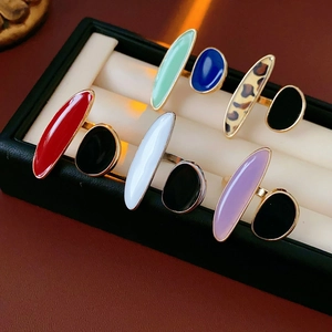 Detail of colorful oval enamel rings with golden frames in a black jewelry display box