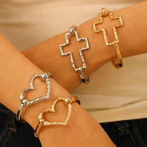 Set of gold and silver hammered metal bangles featuring heart and cross silhouettes