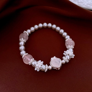 Close-up of pearl and pink quartz bracelet with heart pendant on red silk background