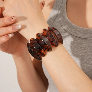 Close-up of tortoise shell resin bracelet featuring wide geometric links on a model wrist