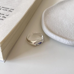 Minimalist 925 sterling silver irregular ring on a white ceramic tray with book pages