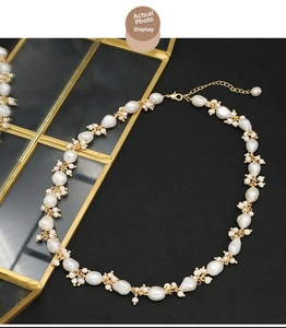 Macro shot of irregular baroque pearl necklace with golden lobster clasp on black background