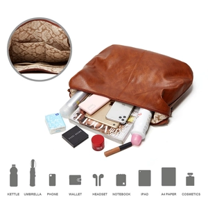 Detail showing the large capacity interior of a brown leather tote bag with various items