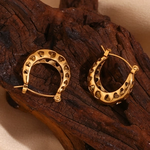 Macro shot of gold-plated hollow heart pattern on U-shaped stainless steel hoop earrings