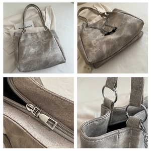 Macro view of grey-brown tote bag featuring vintage texture, silver ring handle and black bead chain