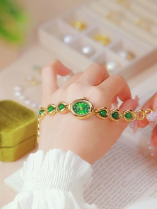 Close-up of gold chain watch featuring green jade dial worn on a woman's wrist