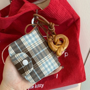 Detail of blue plaid coin purse with resin buckle and pretzel charm held by hand