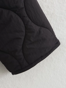 Close-up of black quilted cotton jacket featuring wavy stitching and textured fabric