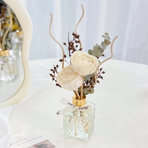 Detail of white rose eternal flowers and eucalyptus in a textured glass aroma bottle