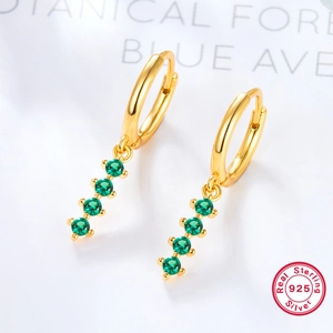 Detailed macro view of 925 sterling silver gold earrings with emerald green gemstones