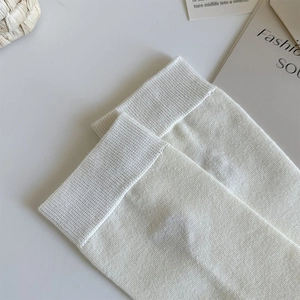 Detail shot of cream knitted crew socks featuring high-quality ribbed cuffs and cotton texture