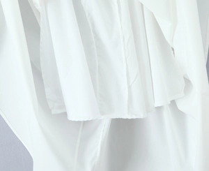 Détail de l'ourlet de la robe blanche montrant les coutures et la texture du tissu
