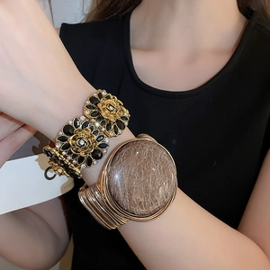 Detail of vintage French style floral bracelet and gold wire wrap bangle on wrist