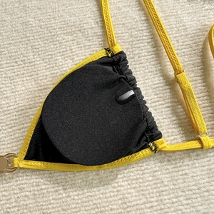 Detail of yellow ribbed bikini cup with black lining and removable pads and metal rings
