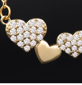 Macro shot of triple heart necklace pendant with cubic zirconia and gold plating