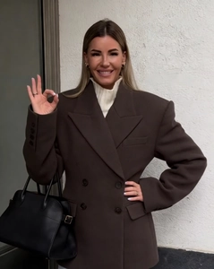 Detail of dark brown double-breasted blazer styled with white turtleneck and black tote bag