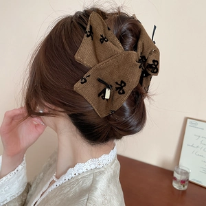 Close-up of brown herringbone bow hair claw with elegant black embroidery on hair