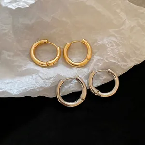 Minimalist thick hoop earrings in gold and silver finish with a polished metallic texture