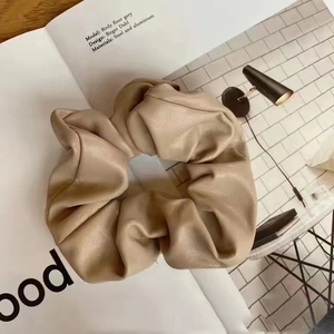Macro detail of beige PU leather scrunchie showing luxury lychee texture and pleated design