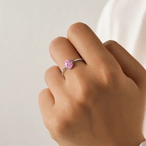 Close-up of S925 sterling silver ring featuring a pink oval zircon on a person's finger
