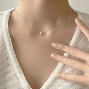 Close-up of minimalist 925 sterling silver ball pendant necklace on a female neck