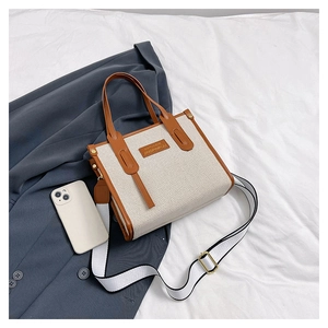 Detail of canvas tote bag with brown leather trim and striped detachable shoulder strap