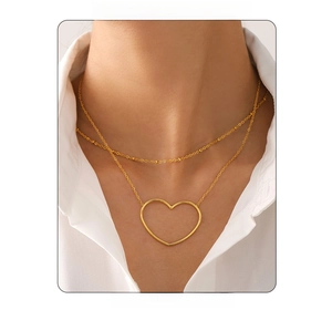 Detail einer zweilagigen Goldkette mit Perlenkette und großem hohlem Herzanhänger
