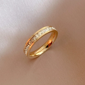 Elegant gold titanium steel ring with a single row of cubic zirconia on silk background