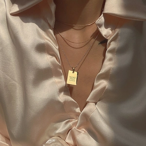 Detailed view of 18k gold plated square pendant with More Self Love engraving on bead chain