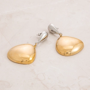 Detailed macro shot of two-tone stainless steel teardrop earrings on marble surface